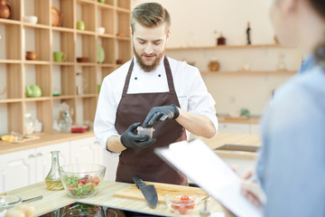 Fototapeta premium Portrait of young professional chef preparing ingredients for culinary masterpiece in modern restaurant kitchen, copy space