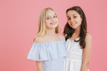 Picture of brunette and blonde cute girls wearing dresses smiling and looking at camera, isolated...
