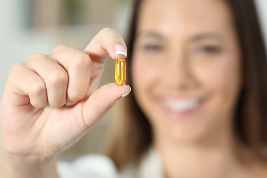 Happy woman hand showing a vitamin supplement pill