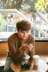 Young Asian man using smart phone during having breakfast, coffee time and summer holiday vacation concepts