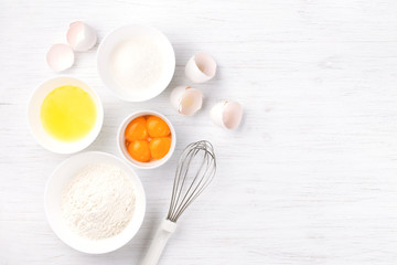 Ingredients for baking sponge cake. Eggs, flour, sugar and whisk. Top view