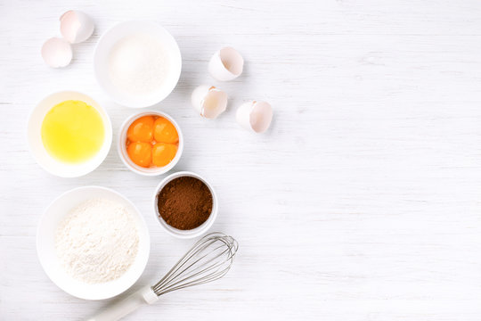 Ingredients For Baking Sponge Cake. Eggs, Flour, Sugar, Cacao And Whisk. Top View