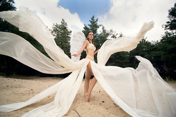 Fototapeta na wymiar Girl with white angel wings in forest