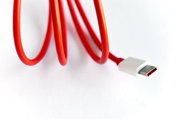 Close-up of red curled USB cable on white background