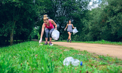 Two girls picking up trash while plogging outdoors