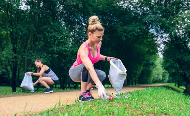 Girl crouching with bag picking up trash doing plogging