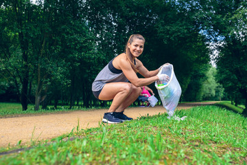 Girl crouching with garbage bag looking at camera doing plogging