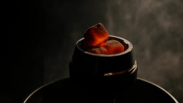 Hot coals in the hookah bowl in darkness closeup. black background