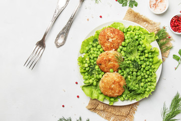 Fish meatballs or cutlets from sea cod with green vegetables, top view
