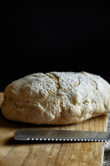 bread with knife on a black background flour on the table