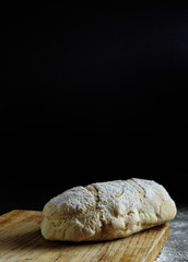bread on a black background flour on the table