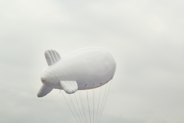 White inflatable dirigible with a place for a logo on a background of a gray sky with clouds. Copy space © alexey_arz