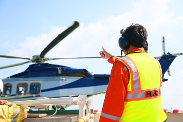 Helicopter Landing Officer communicating with pilot and copilot for service on ground and support as the pilot required. The helicopter landing on the deck in oil and gas platform