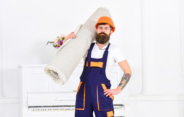 Moving out. Worker holding roller carpet. Guy in orange helmet walking in front of white wall