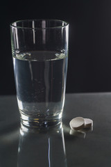 Glass with efervescent tablet in water with bubbles isolated on white