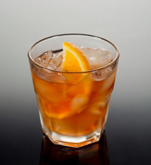 Closeup glass of negroni cocktail decorated with citrus on dark background.