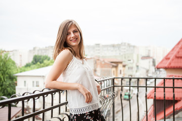 Portrait of a woman with brown hair smiling at camera while sitting at the balcony