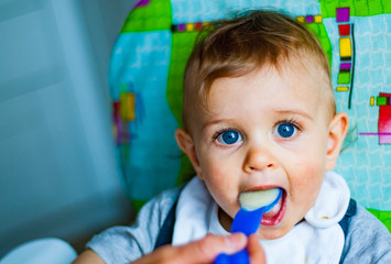 Fototapeta na wymiar baby boy eating food with spoon at home