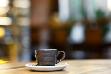 Fototapeta premium Gray ceramic cup on the background of a cafe with space for text