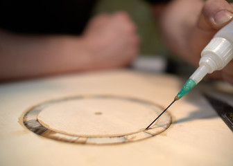 The guitar master pastes the rosette into a classical guitar.