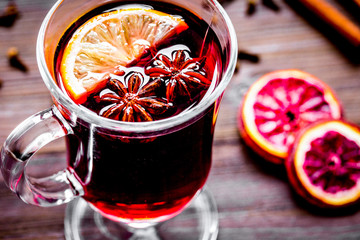 mulled wine with spices in cup on wooden background