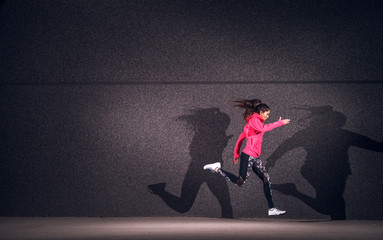 Expressionism of fit beautiful girl running with double shadow.