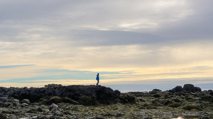 Man sihouette on Icealnd rock formatoin beautiful golden sky