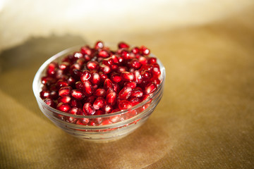 Pomegranate in glass bowl on gold background, healthy food