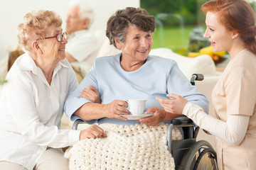 Meeting of happy and smiling senior women and caregiver in the sanatorium