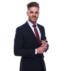 smiling businessman in navy suit and red tie fixing his sleeves