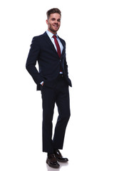 smiling handsome businessman with beard standing with hands in pockets