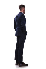 turned businessman in navy suit looks to side