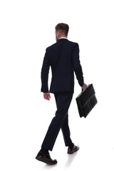 back of businessman in navy suit walking an looking to side