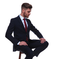 handsome businessman sitting on chair looks down to side