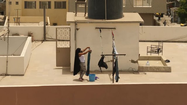 Muslim woman hanging laundry to dry on rooftop in Dakar, Senegal, Africa.