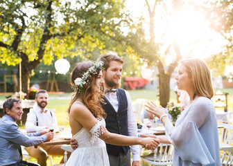 Young girl congratulating bride and groom at wedding reception in the backyard.