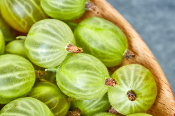 Close up picture of ripe gooseberries in a wooden bowl, shallow depth of field.