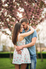 Fototapeta premium Young couple in love resting in the blooming garden. white blooming trees