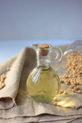 Soy bean oil in glass bottle with soybeans around it.