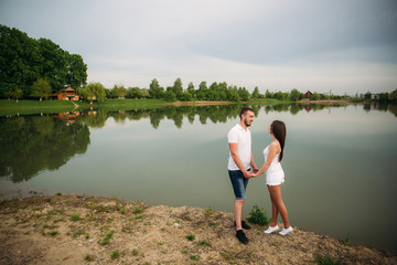 Fototapeta na wymiar Dating in park. Love couple standing together on ground near the lake. Romance and love