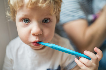 A happy toddler boy brushing his teeth at home. Close up.