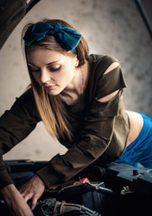 A beautiful girl repairs and maintains a car in the garage. Women in Men's Professions