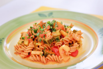 Pasta with zucchini, tomatoes and peppers. Fusilli dressed with tomato sauce, courgettes, aubergines and peppers. Pasta with vegetables, ready to eat.