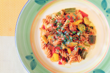 Pasta with zucchini, tomatoes and peppers. Fusilli dressed with tomato sauce, courgettes, aubergines and peppers. Pasta with vegetables, ready to eat.