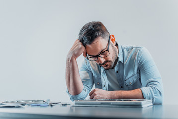 Computer technician looking in despair at laptop. Trouble with repairing laptop computer.