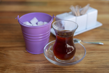 A glass of tea and sugar refined on a wooden table