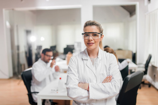 Portrait of smiling female scientist wearing safety glasses.