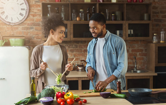 Happy black couple preparing salad in kitchen