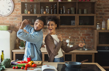 Black couple dancing near table with food in kitchen