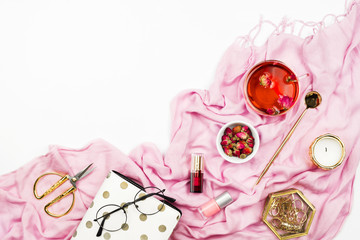 Feminine lifestyle flatlay with pink scarf, hibiscus tea, candles, planner and other accessories on white